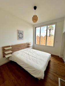 Un dormitorio con una gran cama blanca con ventana. en Bel Appartement face mer, en Billiers