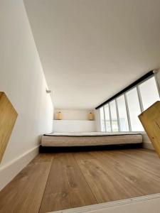 Habitación blanca con cama y suelo de madera. en Bel Appartement face mer, en Billiers