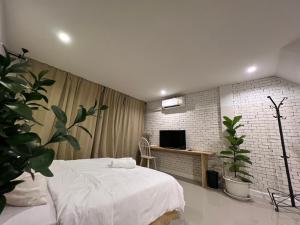 a bedroom with a bed and a tv and plants at Vanilla house in Nonthaburi