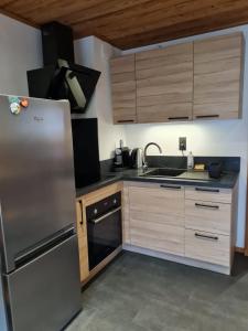 une cuisine avec un réfrigérateur en acier inoxydable et des armoires en bois dans l'établissement Le refuge, à Samoëns 6 autres photos