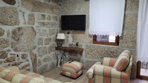 a stone walled living room with chairs and a television at Casa da Fonte in Castro Daire