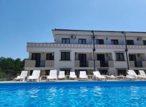 a building with white chairs and a swimming pool at Vrnjački Kos in Vrnjačka Banja