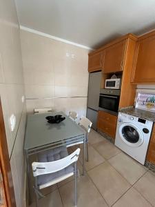 een keuken met een tafel en stoelen en een wasmachine bij Apartamento Rota do Sol in Armação de Pêra