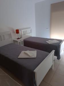 twee bedden in een kamer met twee handdoeken erop bij Apartamento Rota do Sol in Armação de Pêra +6 foto's