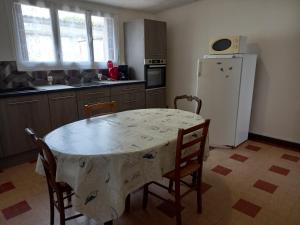 a kitchen with a table with chairs and a white refrigerator at Maison proche plages OMAHA BEACH in Englesqueville-la-Percée