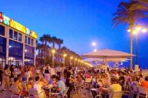 a large crowd of people sitting at tables at night at ruzafa oceanograf science center in Valencia