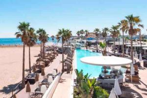 a resort with a pool and palm trees and the beach at ruzafa oceanograf science center in Valencia