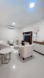 Una sala de estar blanca con un sofá y un televisor. en Stylish house close to tourist attractions, en La Libertad
