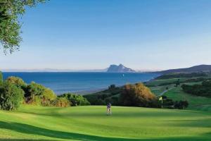 a man standing on a golf course with the ocean in the background at Costa by Hawkins Algeciras - Exterior 2A in Algeciras