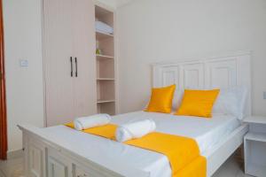 Dormitorio blanco con almohadas amarillas en una cama en LTM Stays ,Buxton Point , Mombasa, en Mombasa