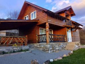 a log cabin with a porch and a deck at Cabana Cristalul din Apuseni in Ciuruleasa