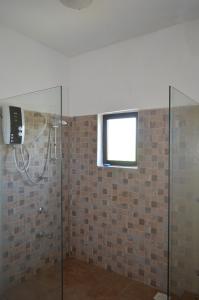 y baño con ducha acristalada y ventana. en Galu Inn en Diani Beach