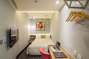 Habitación pequeña con cama y escritorio con ordenador portátil. en V-one Hotel - Ningxia No. 2 Inn en Taipéi