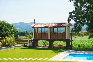 a small house with a deck next to a pool at Casa Os Lindeiros in Arzúa