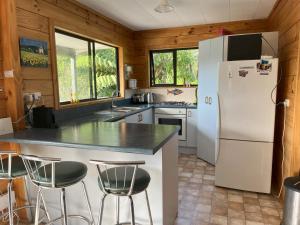 a kitchen with a white refrigerator and some chairs at Picturesque Waikawa - Picton Holiday Home in Picton