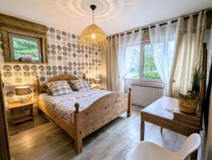 a bedroom with a bed and a table and windows at LE VERTBRUCHE - Gîte avec superbe vue pour 15 pers in La Bresse