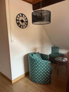 a living room with a chair and a clock on the wall at Home sweet home in La Bresse