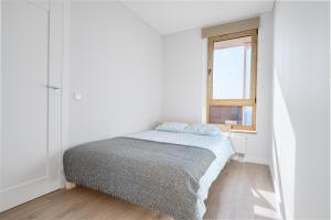 a white bedroom with a bed and a window at Two room Apartment - self check-in in Vilnius