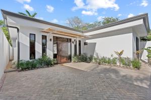 a large white house with a driveway at Swim-Through Glass Pool Villa, 5min Beach in Playa Flamingo