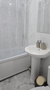 Un baño blanco con lavabo y ducha. en Golden Time, en Almaty