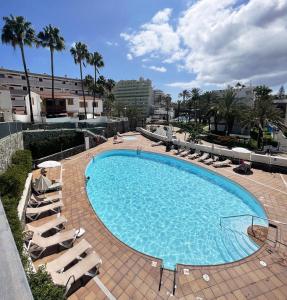 een groot zwembad met ligstoelen en palmbomen bij Duplex Holidays Beach in San Bartolomé