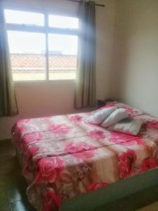 a bedroom with a bed with pink flowers on it at Guarapari 3 quartos com suíte e garagem no Centro de Guarapari in Guarapari