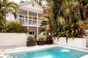 a swimming pool with a fountain in front of a house at The Gardens Hotel in Key West