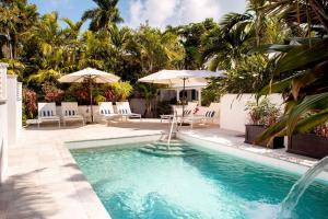 a swimming pool with chairs and umbrellas in a yard at The Gardens Hotel in Key West