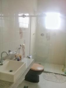 a white bathroom with a toilet and a sink at Guarapari 3 quartos com suíte e garagem no Centro de Guarapari in Guarapari +2 photos