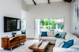 a living room with a couch and a tv at Barefoot Beachfront, Pool, Surf & Private Casita in Playa Grande +19 photos