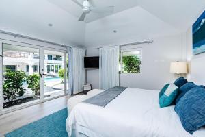 a bedroom with a white bed and a large window at Barefoot Beachfront, Pool, Surf & Private Casita in Playa Grande