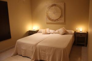 a bedroom with a white bed with two lights on it at Huerto del Medico in Reig