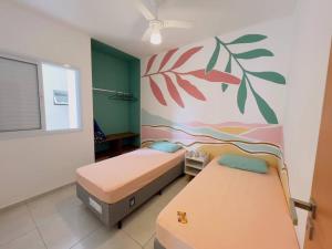 two beds in a room with a painting on the wall at Apê 212 - Piscina, Churrasqueira, 2 Quartos a 600m da Orla Central in Ubatuba +17 photos