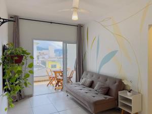 a living room with a couch and a balcony at Apê Jardins 212 - Piscina, Churrasqueira, 2 Quartos a 600m da Orla Central in Ubatuba +17 photos