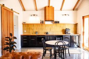 a kitchen with a table and chairs in a room at Three Gums Mudbrick in Crescent Head