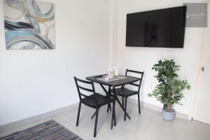 a black dining room table with two chairs and a tv at HHC Apartments Kronos in Paramaribo
