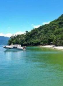ein Boot im Wasser neben einem Strand in der Unterkunft Casa 5 quartos Ilha de Itacuruça RJ in Mangaratiba
