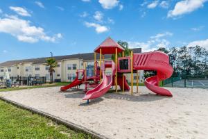 een speeltuin met een rode glijbaan in het zand bij Dream Condo in Kissimmee