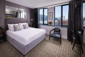 una camera da letto con un letto, una sedia e delle finestre di Titanic Hotel Belfast a Belfast Altre 37 foto