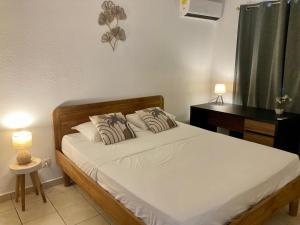 a bedroom with a bed with two pillows on it at Charme Vanillé 2 chambres avec piscine et parking Gosier 5 min plage in Le Gosier +8 photos