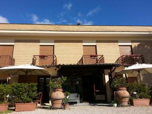 un bâtiment avec des parapluies et des plantes devant lui dans l'établissement Hotel Tempio di Apollo, à Olgiata