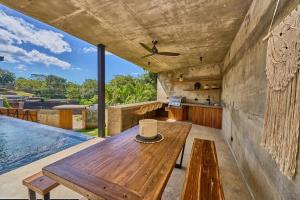 a room with a wooden table and a swimming pool at Buho Vibe Earthy Elegance in Tamarindo
