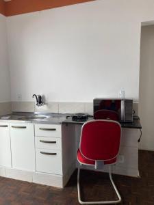a kitchen with a red chair and a microwave at Kits mobiliado in Campinas