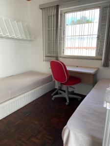a bedroom with a desk and a red chair at Kits mobiliado in Campinas