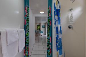 a bathroom with a walk in shower with a shower curtain at Vaka Beach Cottage with AC Unlimited Wifi in Rarotonga