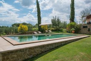 a swimming pool in a yard with a stone wall at Conca d'Oro casale con piscina privata in Foiano della Chiana