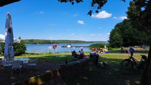 eine Gruppe von Menschen, die auf dem Gras in der Nähe eines Sees sitzen in der Unterkunft Villa Romantica Lenzen in Körbitz