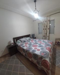 a bedroom with a bed with a quilt on it at Goulmim in Mohammedia