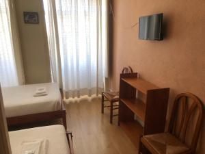 une petite chambre avec un lit, un bureau et une télévision dans l'établissement Corações Unidos "A Pensão", à Alcobaça