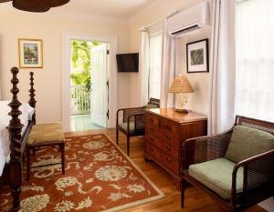 a bedroom with a bed and a dresser and a chair at The Gardens Hotel in Key West